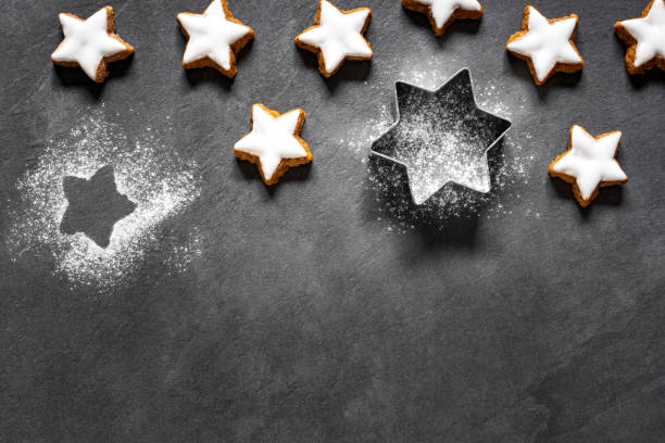 istock Fresh cinnamon star shaped cookies with frosting on black slate background 1069263982