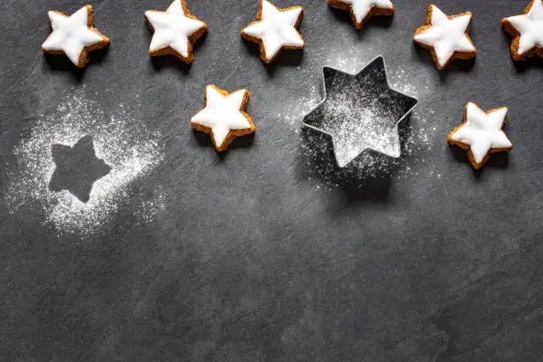 Fresh cinnamon star shaped cookies with frosting on wooden table.
