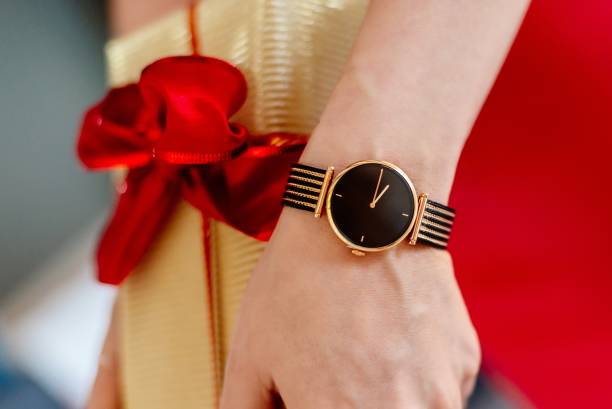 Woman in red dress giving Christmas gift in gold box with red ribbon stock photo