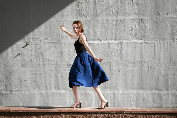 istock young girl posing against a concrete wall, dressed in black, hard light and shadows 1069281118