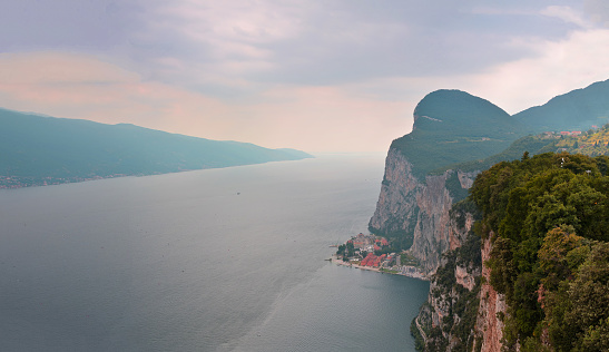 View of the Lake Garda from Terrassa Tremosine, Italy. Panorama of the gorgeous Garda lake surrounded by mountains in the summer on a cloudy day.