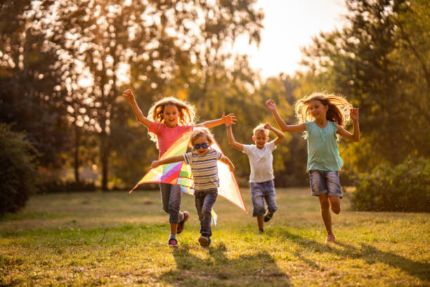 Group of happy children running in public park Happy kids playing in nature with flying dragon children only stock pictures, royalty-free photos & images