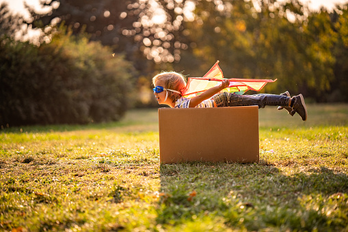 boy playing with a toy tractor outdoors in the summer in the sun