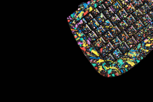 Black keyboard stained with colourful paint splash on black isolated background with copy space.
