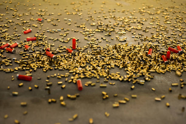 Dozens of gun shells, rounds laying on the floor empty in shalow depth of field after being shot. 9mm, 38mm handguns and shotgun rounds.