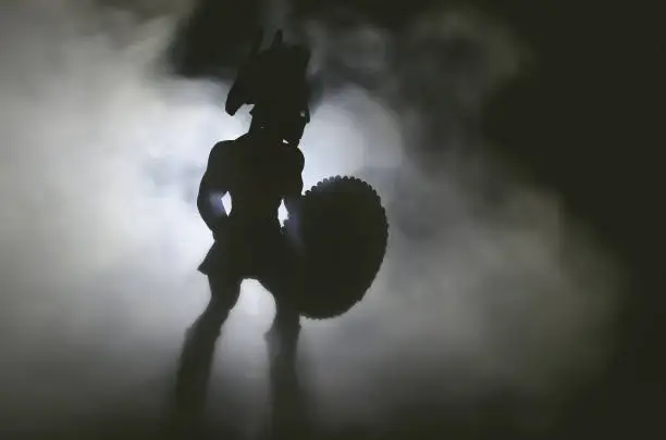 Silhouette of ancient spartan warrior with spear and shield in the smoke.