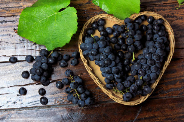 trauben von traube in korb mit herzform auf holztisch, ansicht von oben - grape heart shape fruit bunch stock-fotos und bilder