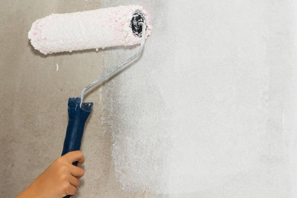istock Close up of painter i'm painting a wall with paint roller. 1069296754