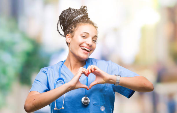 joven trenzas niña afroamericana profesional médico cirujano sobre fondo aislado sonriendo en el amor que muestra el símbolo del corazón y forma con las manos. concepto romántico. - cheerful happiness smiling teenager fotografías e imágenes de stock