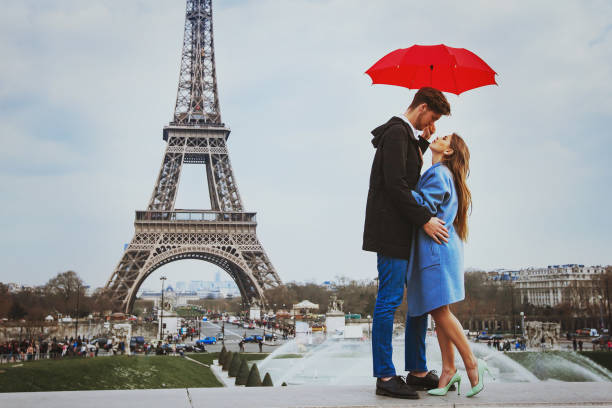 romantic couple in Paris near Eiffel tower in autumn romantic affectionate couple kissing under  umbrella near Eiffel Tower, honeymoon in Paris paris france eiffel tower love kissing stock pictures, royalty-free photos & images