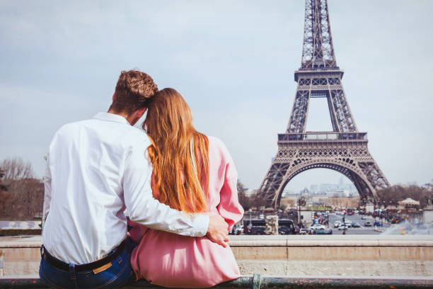 vacanze romantiche in francia, coppia seduta insieme vicino alla torre eiffel a parigi, luna di miele - paris france heterosexual couple couple french culture foto e immagini stock