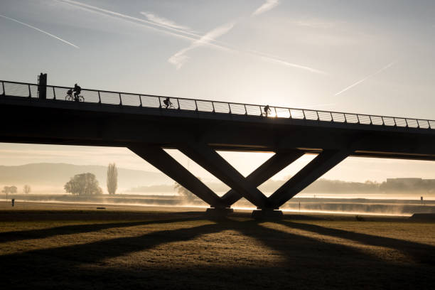rowerzyści jeździć rano we mgle i wschodzie słońca nad mostem - unsolicited zdjęcia i obrazy z banku zdjęć