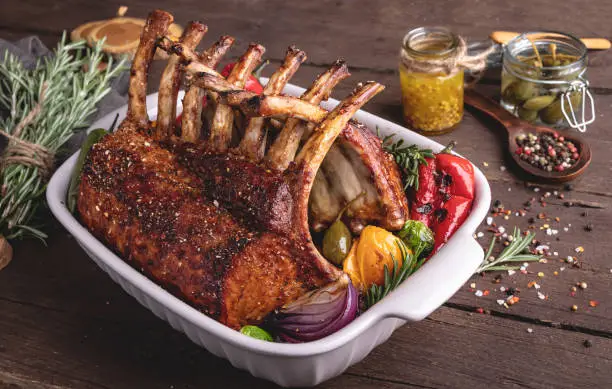 Grilled roasted rack of lamb,meat chops with vegetables in ceramic baking dish.