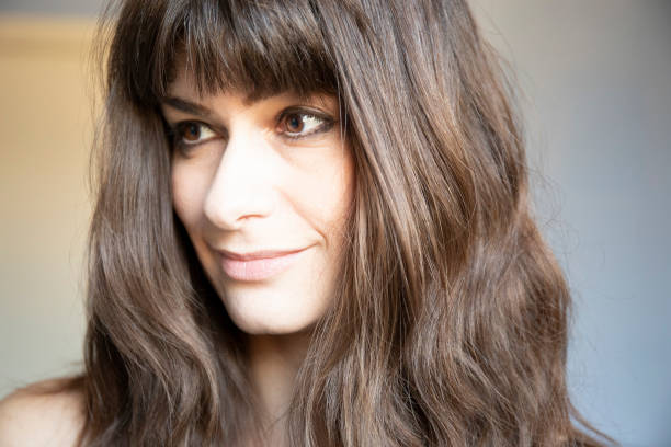 Young woman 3/4 close-up portrait. Caucasian with brown long hair and bangs. stock photo