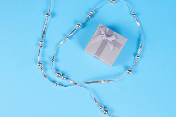 istock Gift box and silver ribbon on blue background. 1069326942