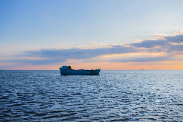 istock small boat silhouette among a sea at the sunset 1069331022
