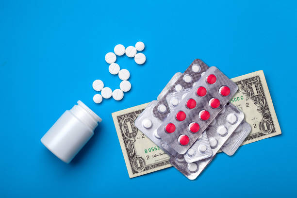 A conceptual background on the pharmaceutical industry. A conceptual background on the pharmaceutical industry and treatment prices, a plastic white bottle for medications with tablets depicting a dollar symbol and next to it lies 1 dollar as an indicator of a low price. inexpensive stock pictures, royalty-free photos & images
