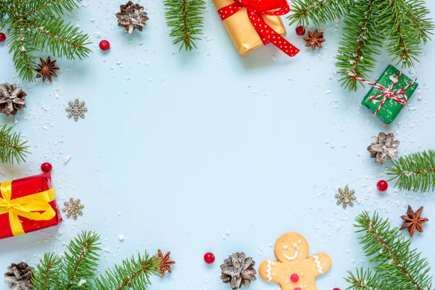 istock Christmas frame made of fir branches, red berries, gift boxes and pine cones on blue background 1069343068