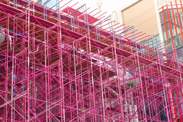 Pink scaffolding on a building. The scaffolding is pink and is being used for construction. The building is a large, white structure