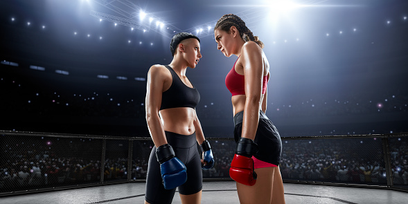 Muscular female Mixed Martial Arts athletes in professional ring face to face
