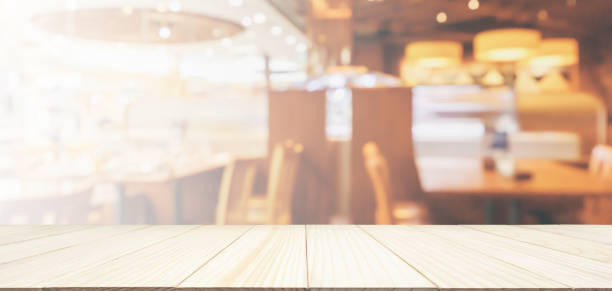 istock Wood table top with Restaurant cafe or coffee shop interior with people abstract defocused blur background 1069359374