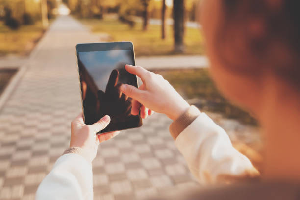 istock Smiling girl using tablet in sunny park alley. 1069359530