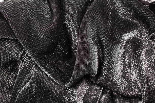 Black and silver background of festive material with wavy folds.