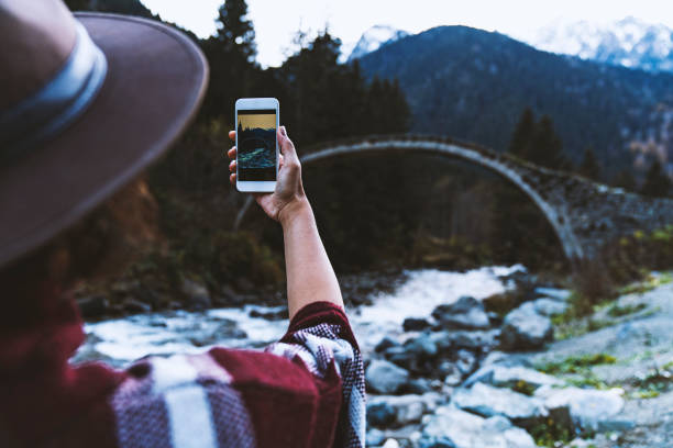 Traveler photographing old stone bridge over the river with her smart phone, Çilanç Bridge, Rize