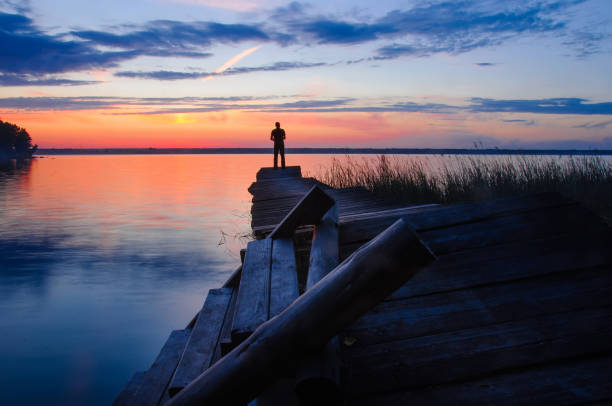 istock Fisher on evening old pier on the lake at sunset 1069378232