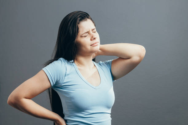 istock Young woman with neck pain over gray background 1069379852