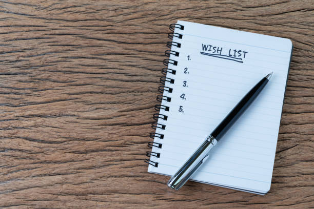 istock Wish list concept, pen on white paper note pad with handwritten headline as Wish List and numbers listed on wood table in soft tone, things wanted or next time purchase or new year event 1069385078