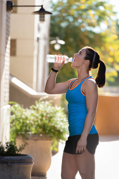 istock Beautiful brunette woman drinking water after exercising 1069398860