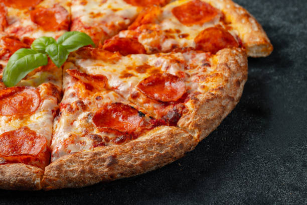 istock Tasty pepperoni pizza and cooking ingredients tomatoes basil on black concrete background 1069399070