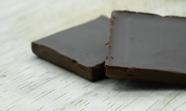 istock Close up dark chocolate in square pieces on wooden background. 1069423390