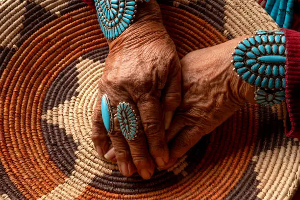 Senior Navajo woman posing with traditional turquoise jewelry inside an authentic hogan