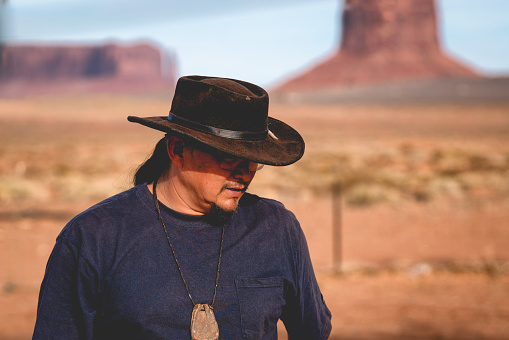 Handsome and rugged traditional Navajo Man portrait outside in Monument Valley Arizona with scenery view