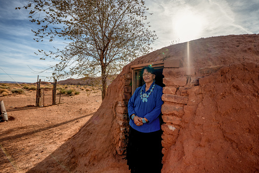Authentic modern and traditional senior navajo woman portrait posing outside a real native american residential structure hogan