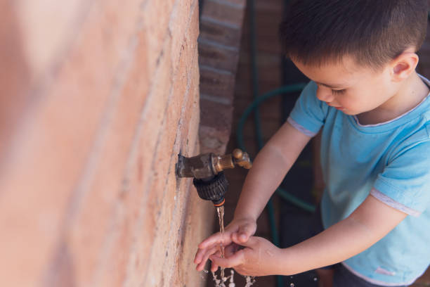 Little boy washing his hands at an outdoor tap stock photo
