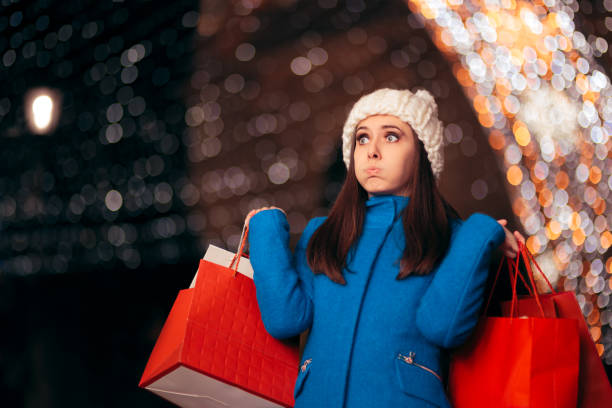 Tired Girl Holding Shopping Bags on Christmas Lights Décor Exhausted stressed holidays buyer feeling fatigued commercial activity stock pictures, royalty-free photos & images