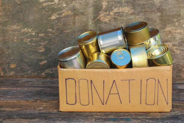 istock Donation box with different canned food on old wooden background. 1069444124