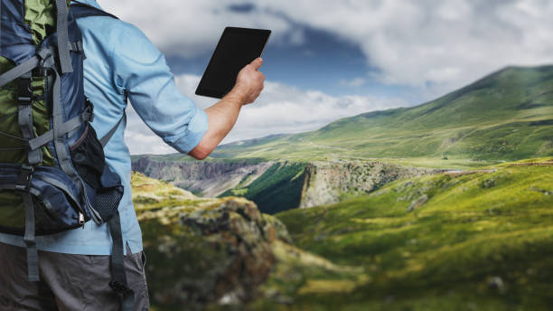 istock Young traveler hiker with backpack looking at the route map in a digital tablet. The concept of a modern adventure 1069465568