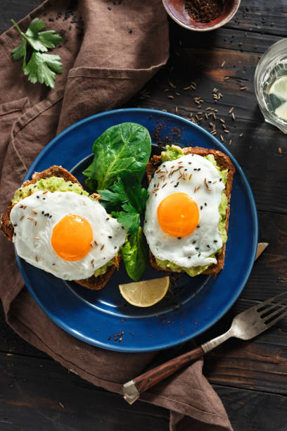 istock Healthy breakfast avocado toasts fried egg cheerful faces Top view healthy table 1069466866