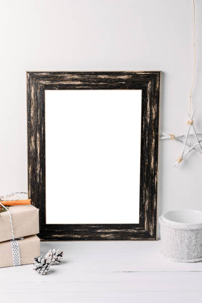 istock Empty white frame mock up. Black wooden frame mockup with christmas decorations on a white background 1069468696