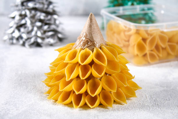 istock How to make a Christmas tree from raw pasta conchiglie. The process of making Christmas trees from pasta, cardboard plates, hot glue and paint or spray. Guide, step by step on the photo.Handmade, DIY. 1069470930