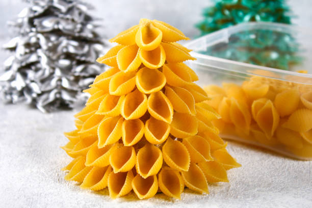 istock How to make a Christmas tree from raw pasta conchiglie. The process of making Christmas trees from pasta, cardboard plates, hot glue and paint or spray. Guide, step by step on the photo.Handmade, DIY. 1069470952