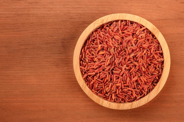 ein foto von einem roten langkornreis, geschossen von oben in einer holzschale auf einem rustikalen dunklen hintergrund mit textfreiraum - camargue red rice stock-fotos und bilder