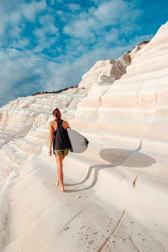 Woman with a surfboard on white cliffs