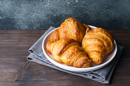 Freshly baked croissants on a plate, dark background, copy space.