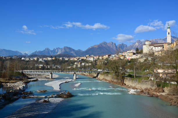 il piave, sacro alla patria, scorre lentamente attraverso la città di belluno in italia - tofane foto e immagini stock