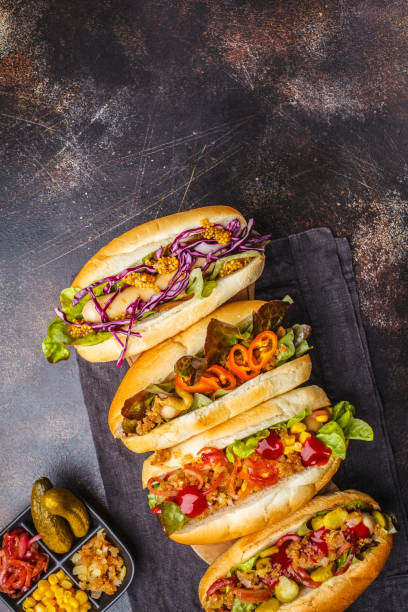 istock Hot dogs with assorted toppings on a dark background, top view. 1069484968